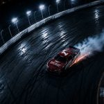Night racing scene showing a single drifting race car on a lit track with smoke and sparks, representing control and risk in high-pressure situations.